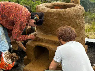 People crafting a large clay pot outdoors in a natural setting.