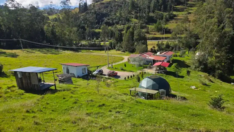 Scenic view of La Pacha Casa de Saberes with green hills and traditional buildings.